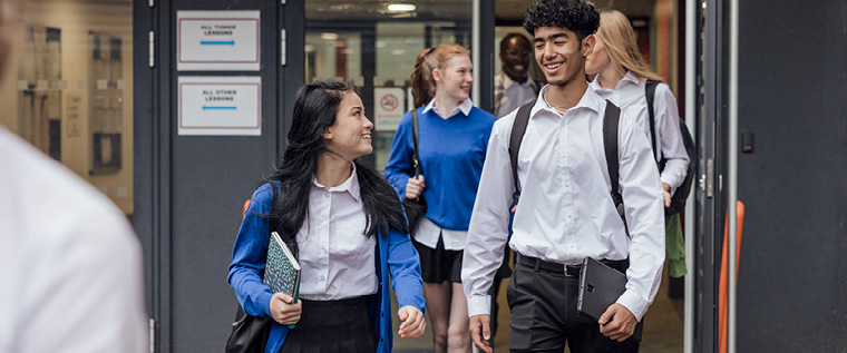 A group of students in school uniforms walking in front of a building