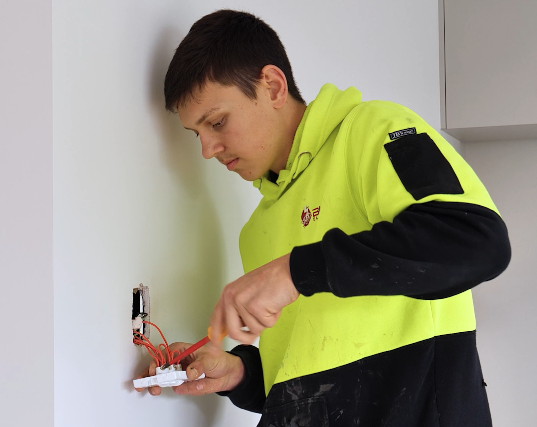 Ky screwing light switch into wall