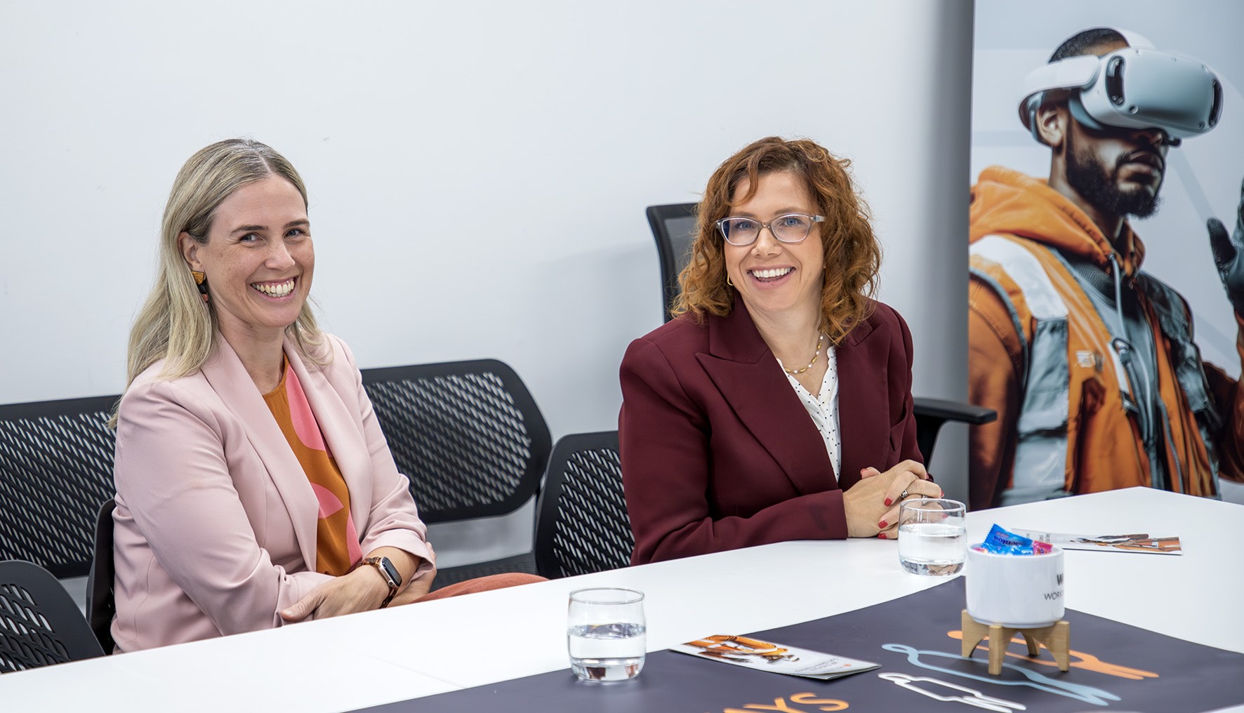 Two people sitting at a desk smiling