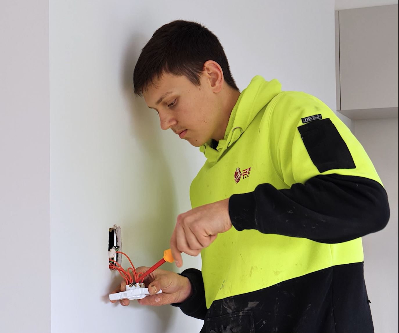 Ky screwing light switch into wall