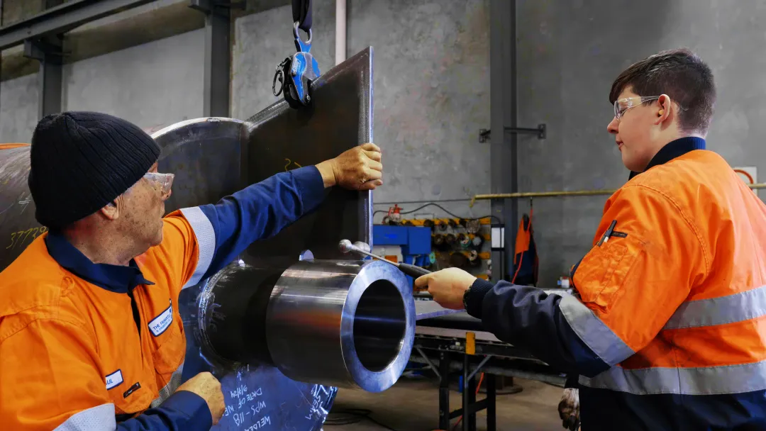 apprentices trainees programs we are recruiting for host employer metal work young apprentice or trainee with mentor working high-vis safety glasses blue-collar worker clothing engineering factory industry job machine man mechanic metalworking person pipe technician workwear