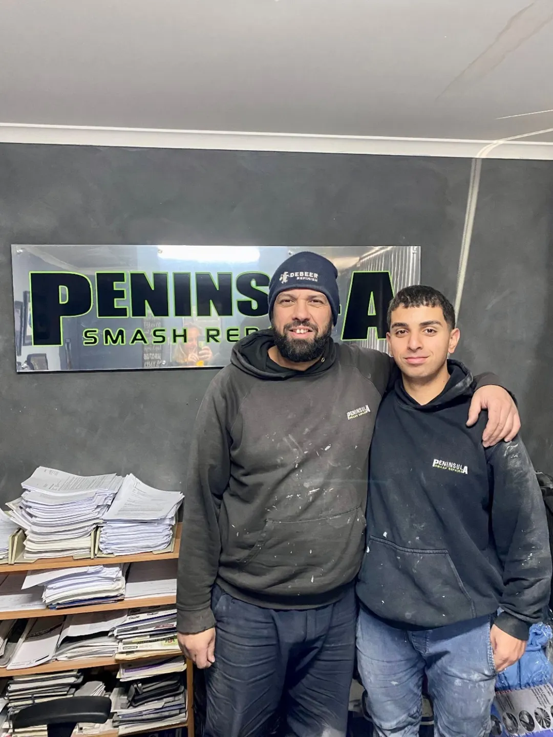 young man apprentice Employers How apprentices and trainees can grow your business Ben apprentice panel beater standing with work colleague indoors clothing human beard human face indoor jacket jeans man person smile wall