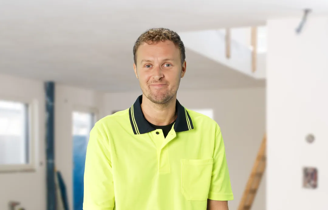 Air conditioning mechanic wearing hi vis standing in a construction site