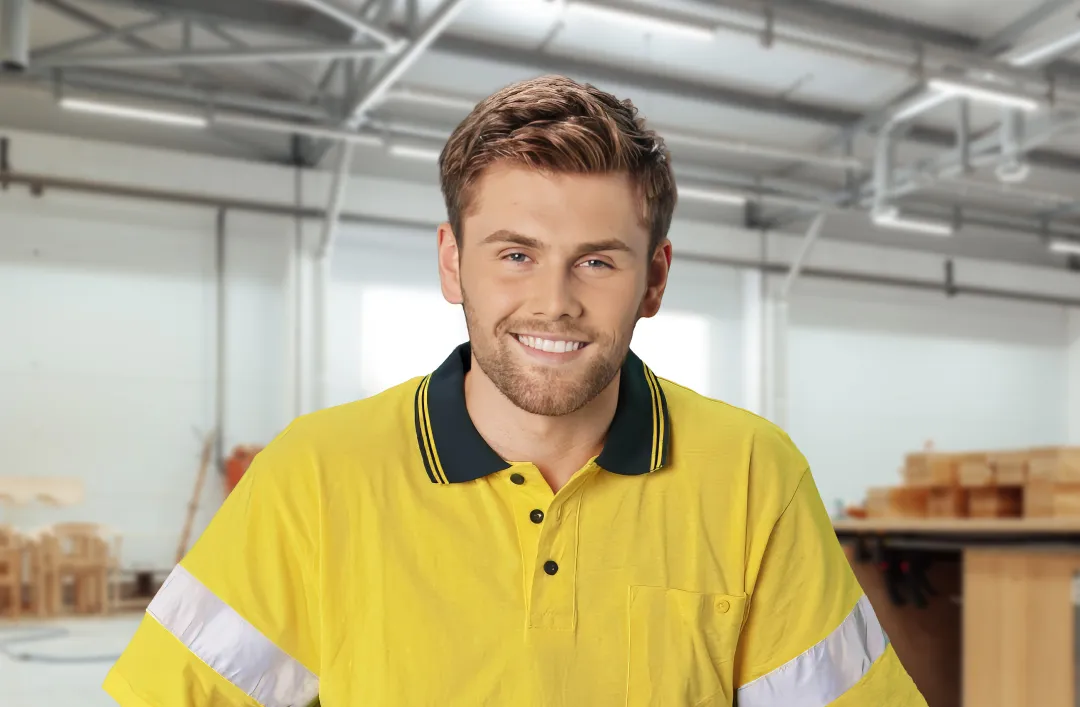 Man wearing hi vis standing in workshop surrounded by wooden building materials