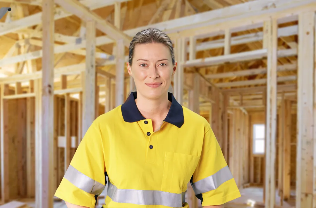 Woman wearing hi vis standing at work site with wooden beams behind her