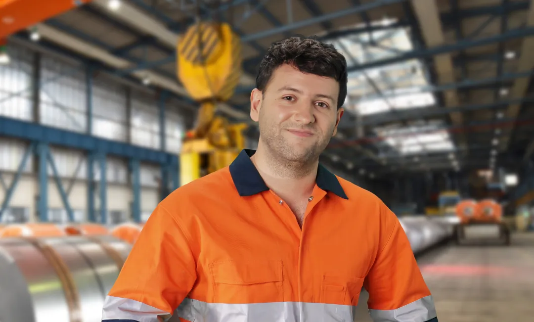 Sheet metal worker wearing hi vis work shirt standing in warehouse surrounded by equipment