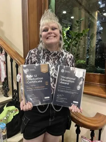 Person with a wide smile holding certificates
