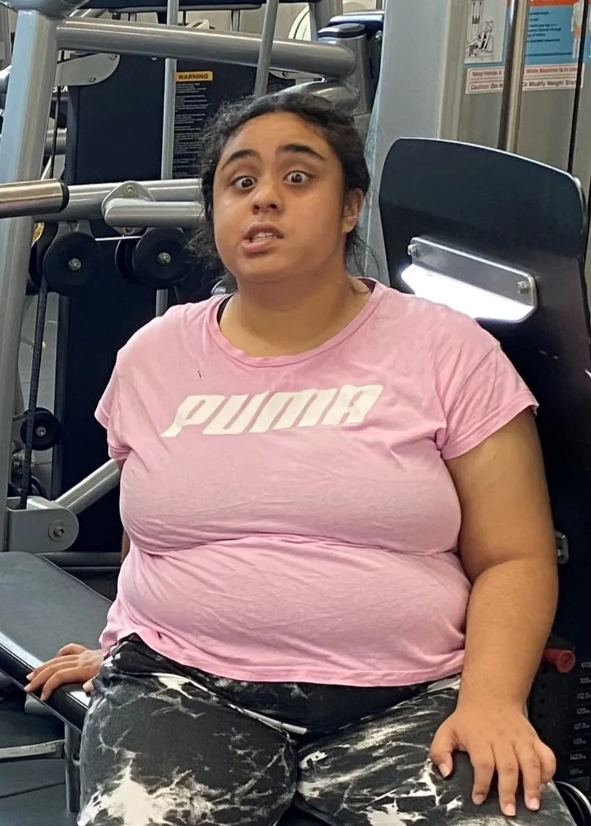 A woman wearing a pink T-shirt and activewear sitting down