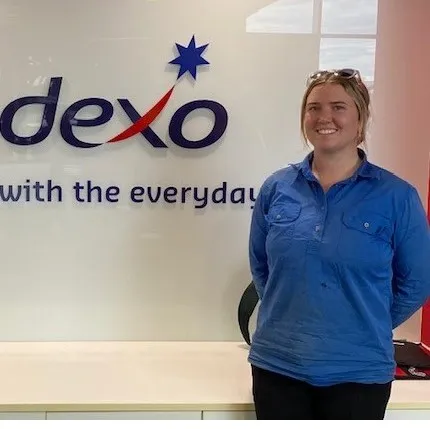 Person standing in front of a "sodexo" logo with tagline.