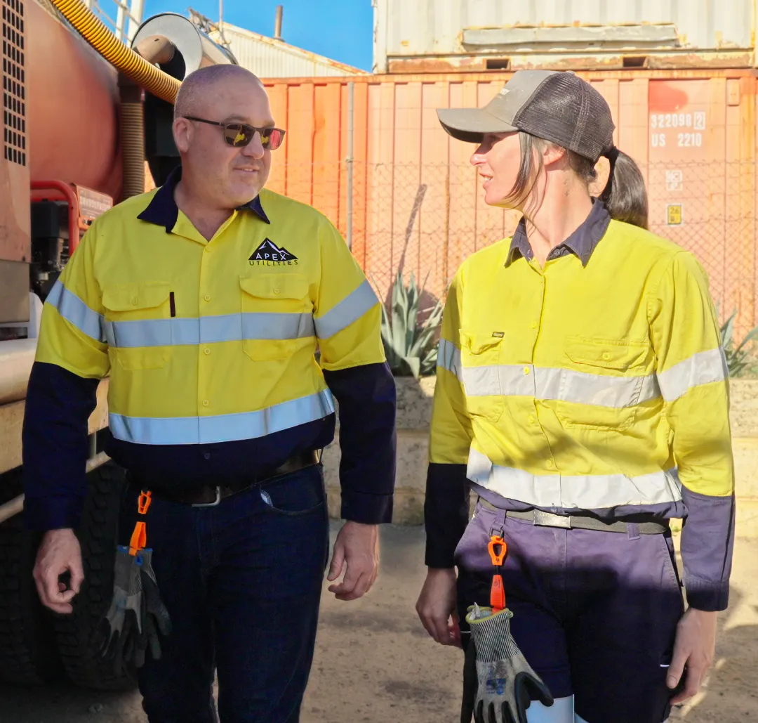 Two workers walking beside large shipping containers