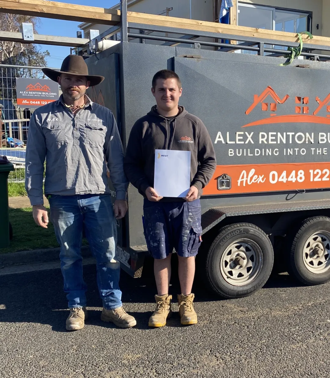 Two people standing outside in front of a trailer