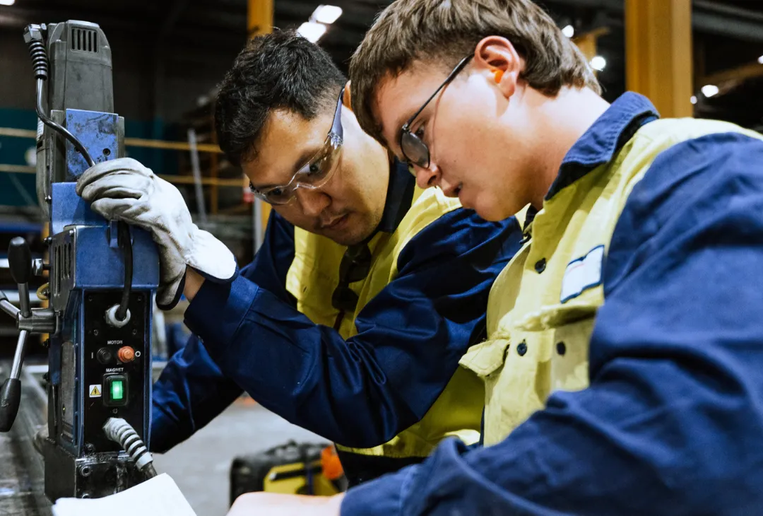 An apprentice working with a supervisor in a workshop.