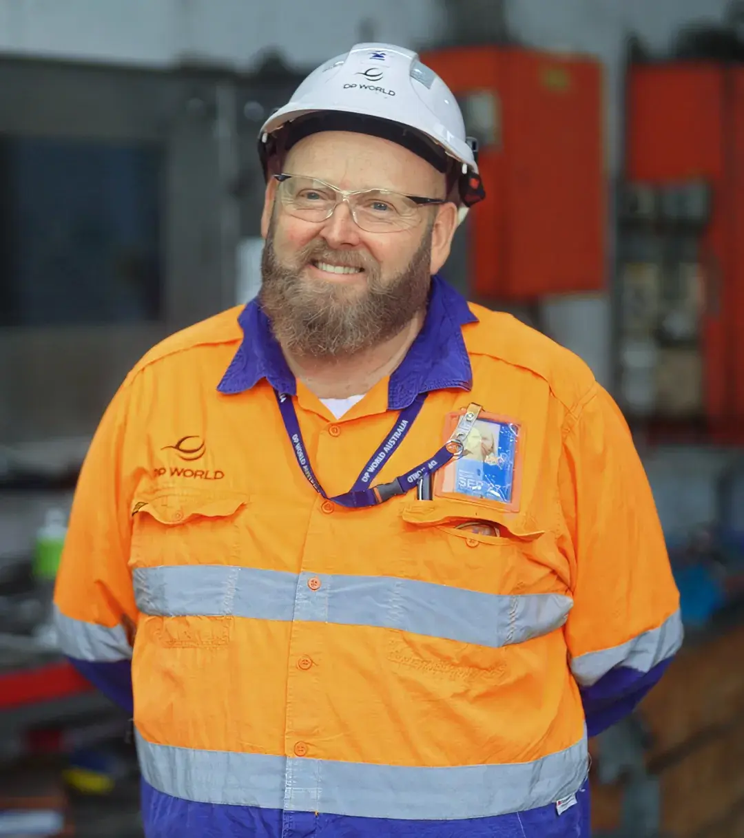 Worker wearing orange high visibility work shirt and hard hat while smiling