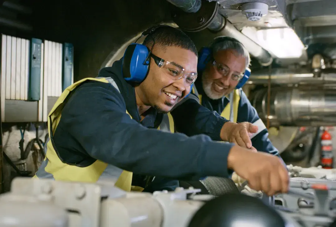 Smiling male mechanic working while supervisor oversees