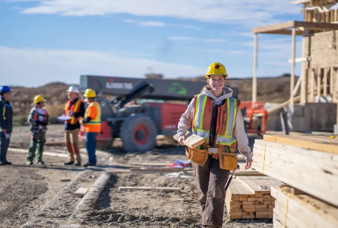 Female construction worker smiling and walking outdoors through a work site