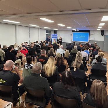 Group of people in a room watching a presentation
