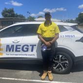 First Nations man wearing high visibility uniform standing in front of vehicle with “MEGT” printed on the side.