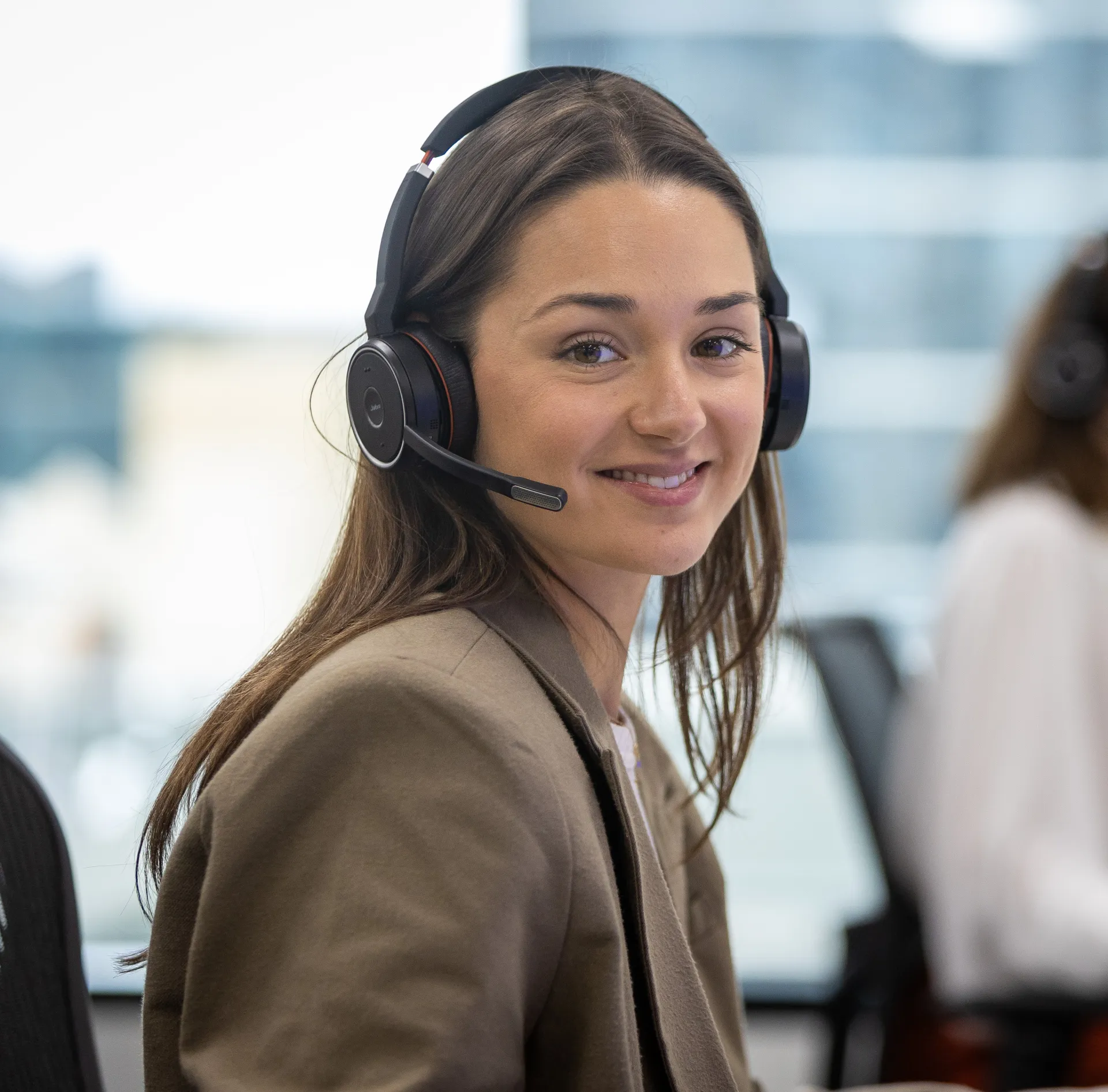 Woman wearing a headset sitting at a desk in an office setting