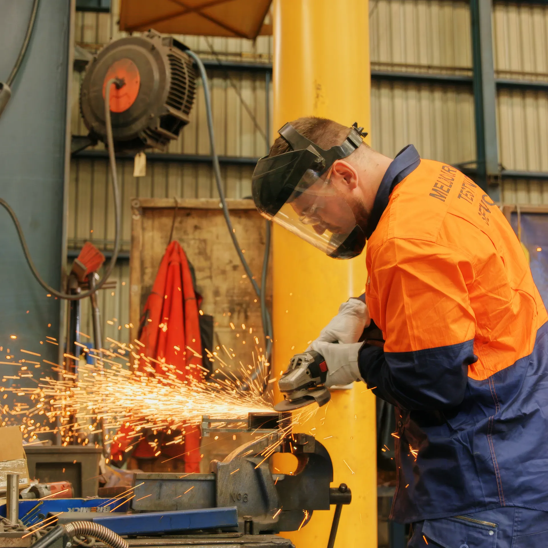 Worker wearing protective mask and gloves while using a metal grinder