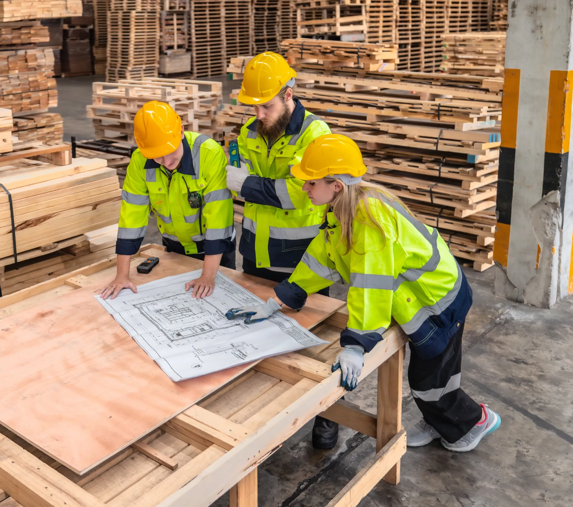 Three workers in high-vis clothing reviewing a blueprint.