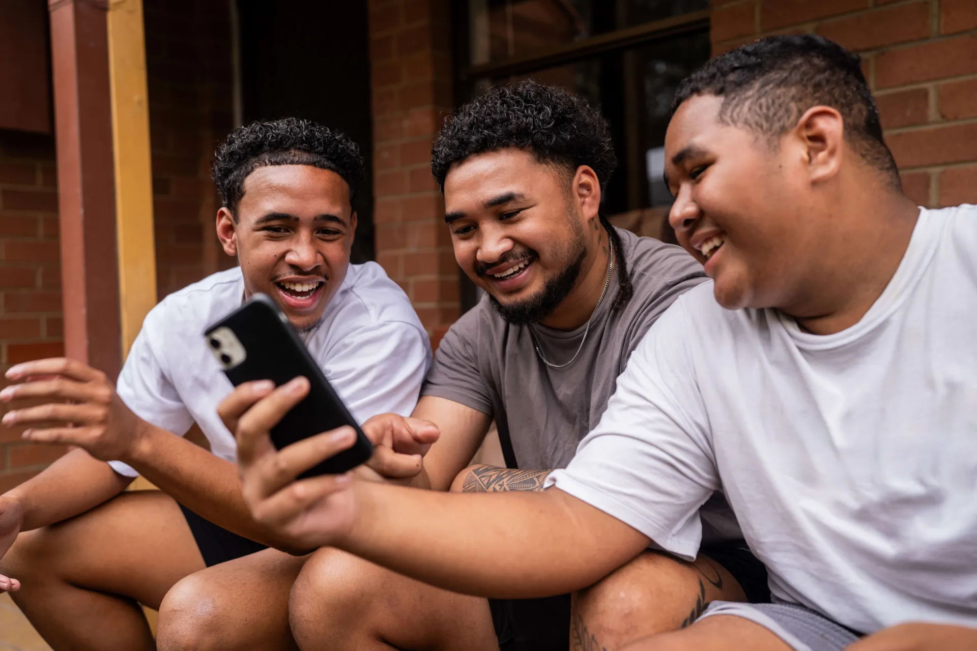 Group of boys sitting together looking at a phone and laughing