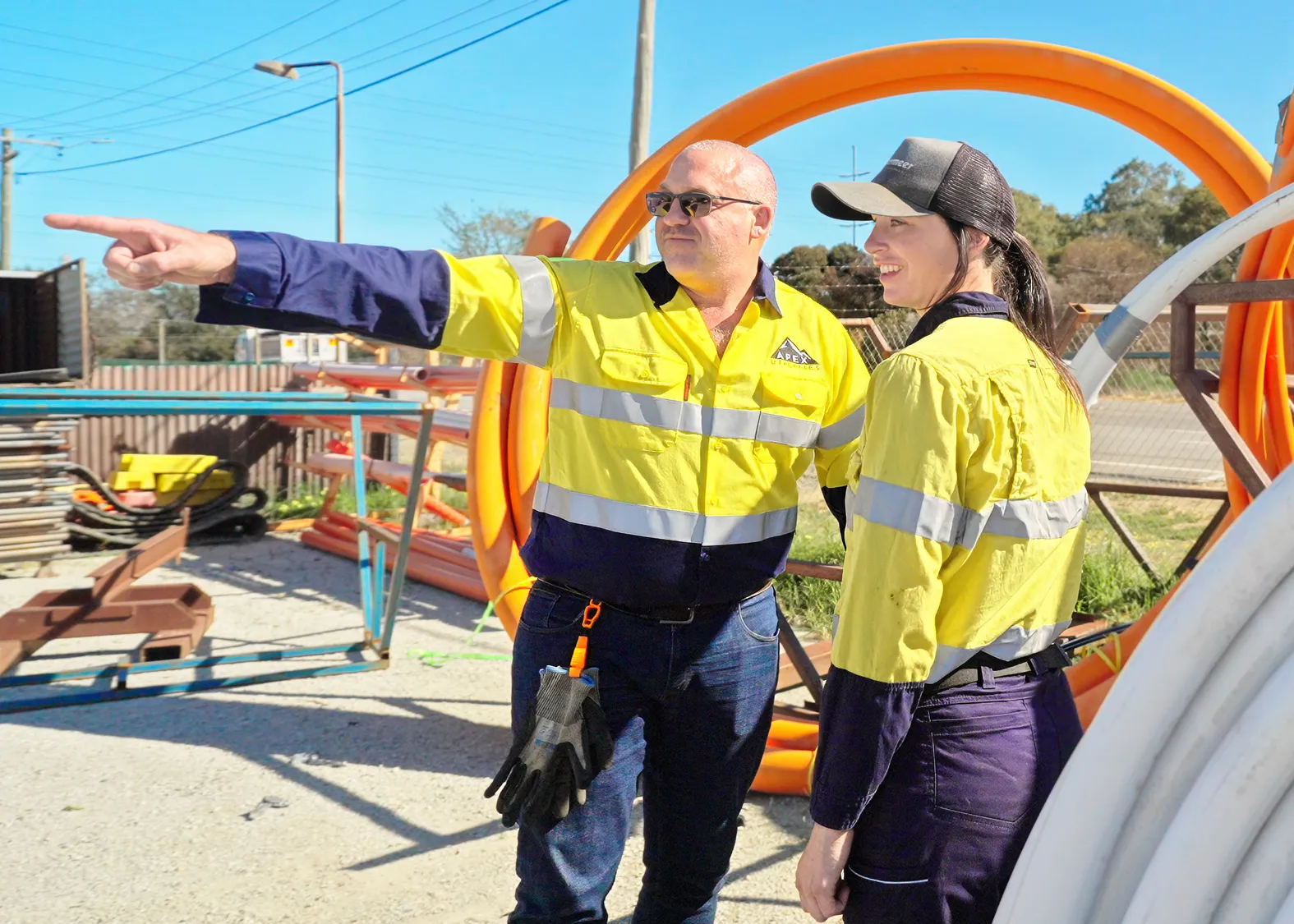 Two people on a work site wearing yellow high visibility workwear