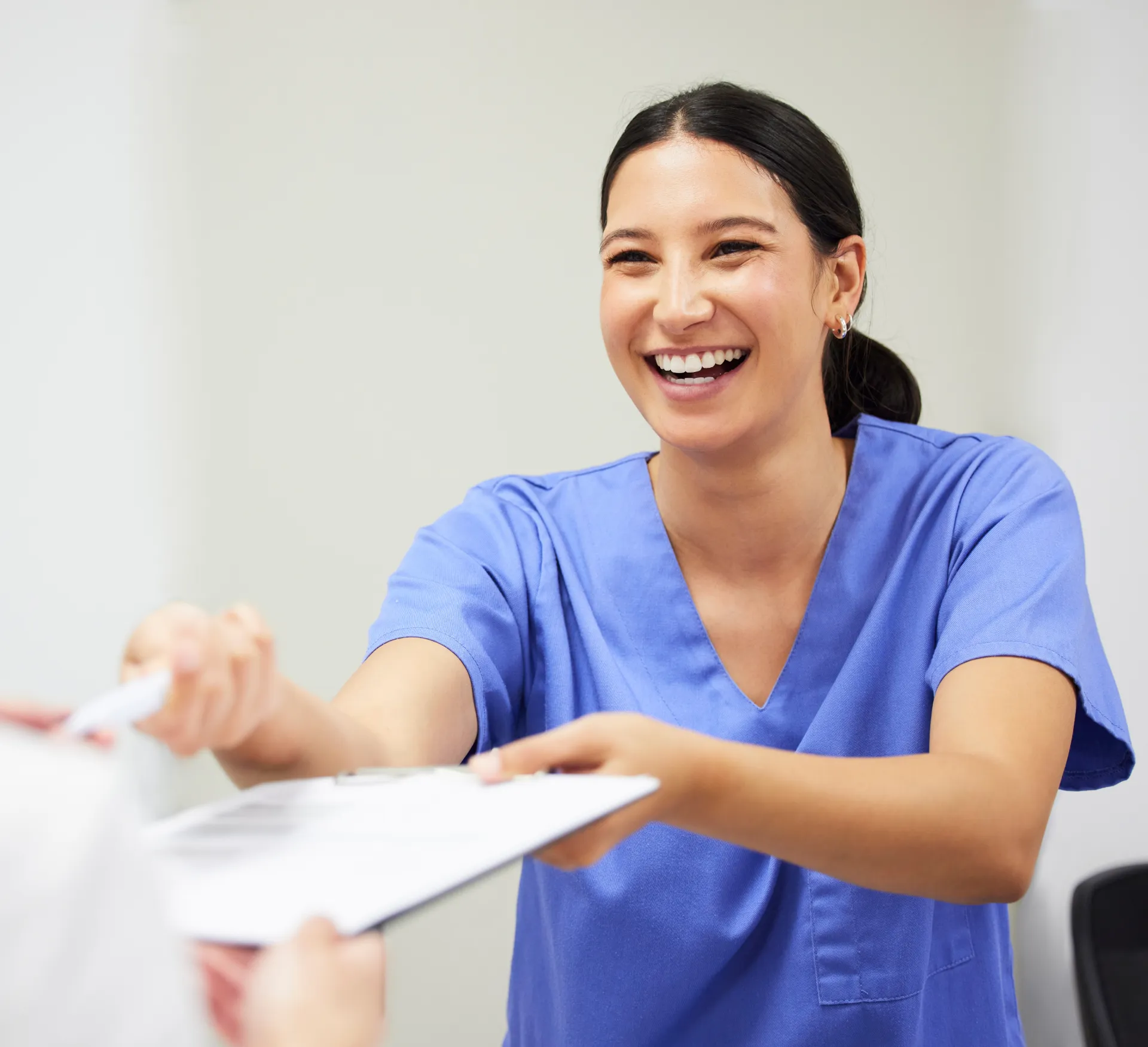 Healthcare worker handing someone a clipboard while smiling