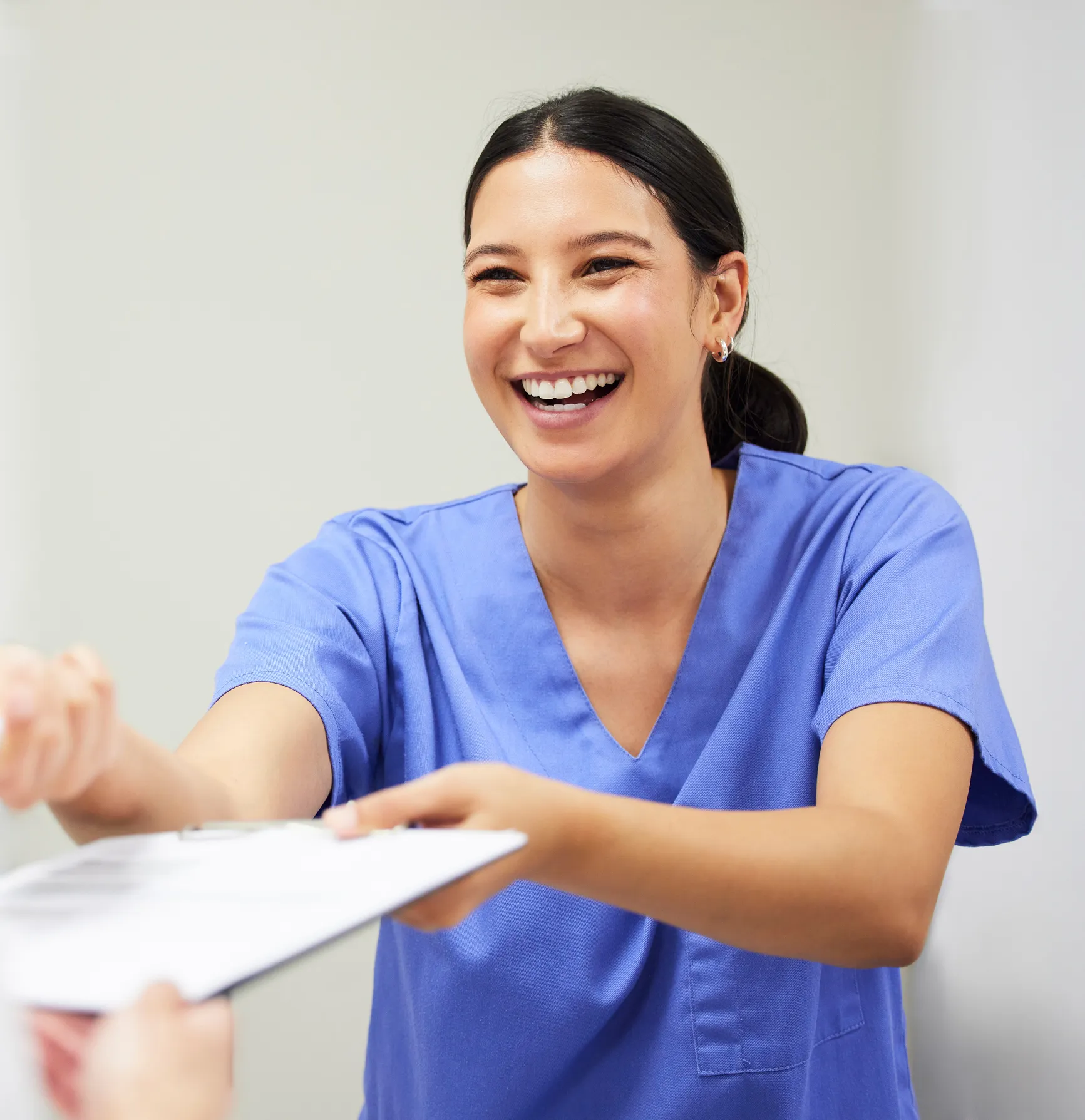 Healthcare worker handing someone a clipboard while smiling