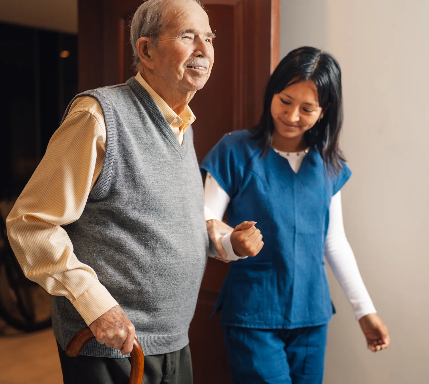 A healthcare worker assisting an elderly man as they walk together.