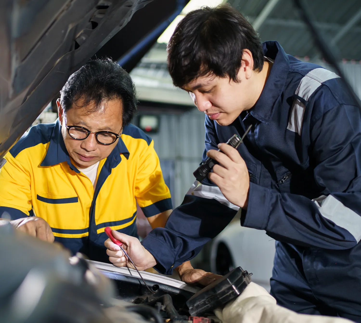Two mechanics inspecting a car engine together.
