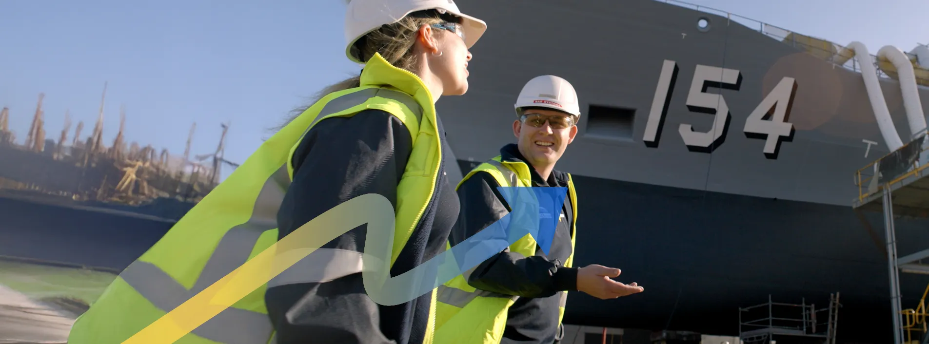 Two workers standing outdoors in ship yard