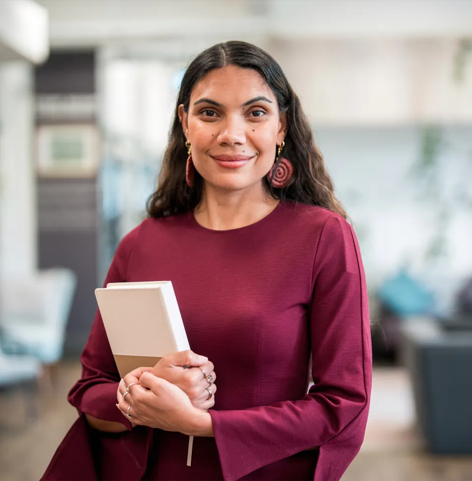 Person holding a notebook in an indoor workspace.