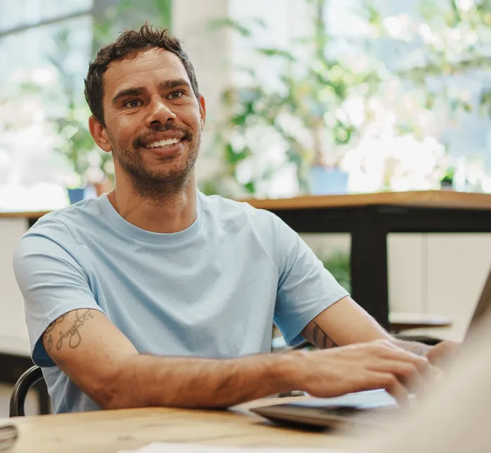 Person sitting at a table using a laptop in a bright indoor space.