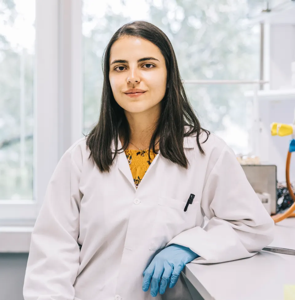 Person in a lab coat standing in a laboratory workspace.