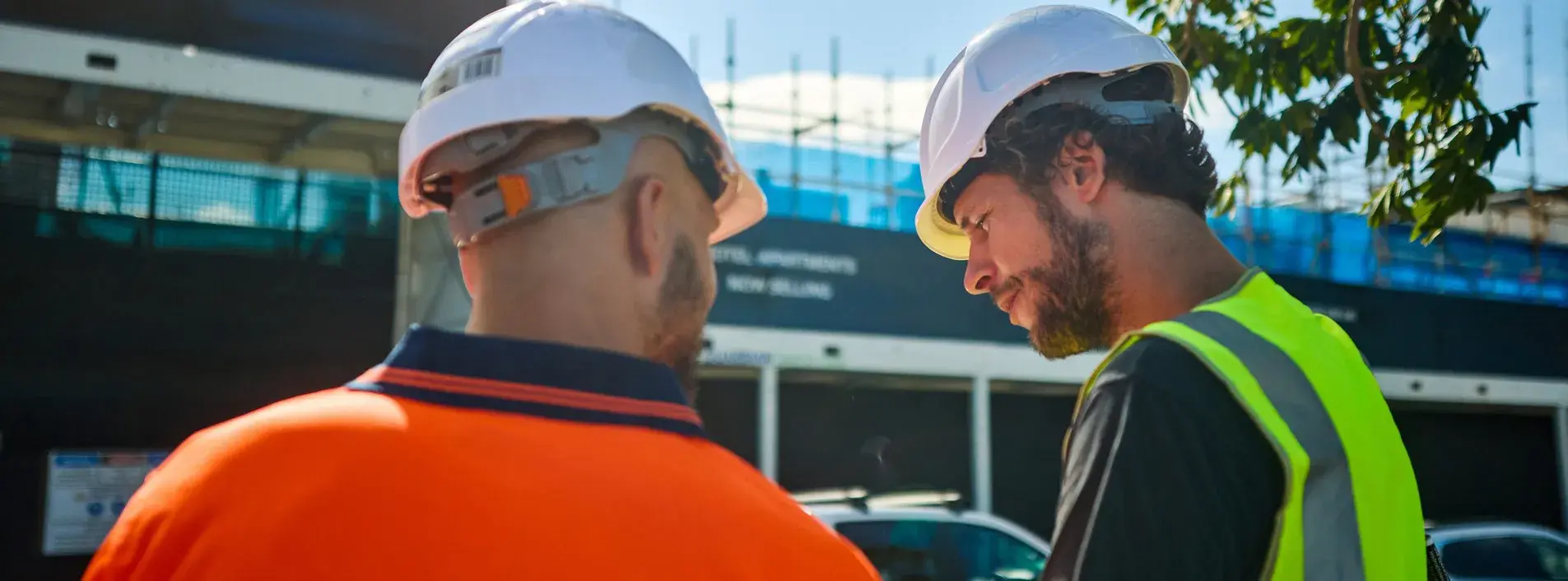 Two workers standing outdoors infront of a worksite