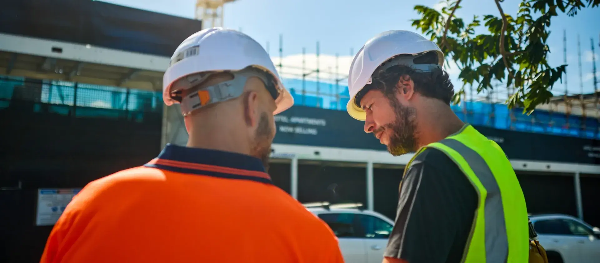 Two workers standing outdoors in front of a worksite