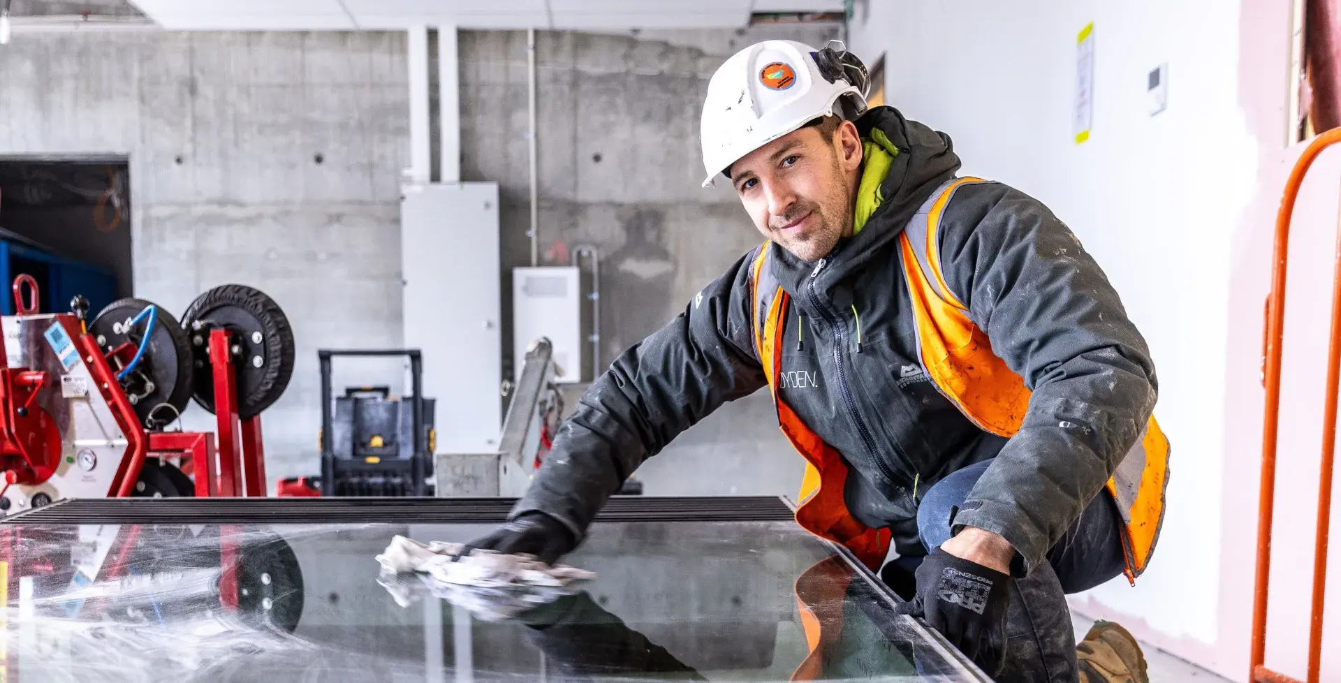 Worker wearing hi vis and PPE working on glass in a warehouse