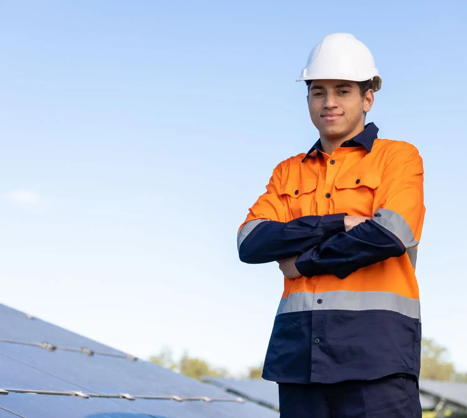 Worker wearing orange high visibility work shirt with arms folded standing outdoors
